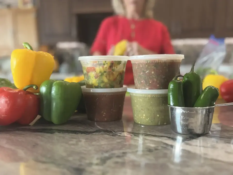Four fresh Salsalita’s salsas with colorful peppers in Colita’s kitchen